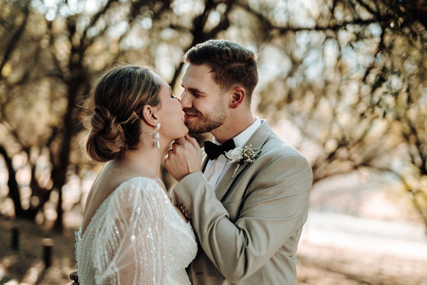 Intimate wedding portrait of couple laughing together in wooded setting.