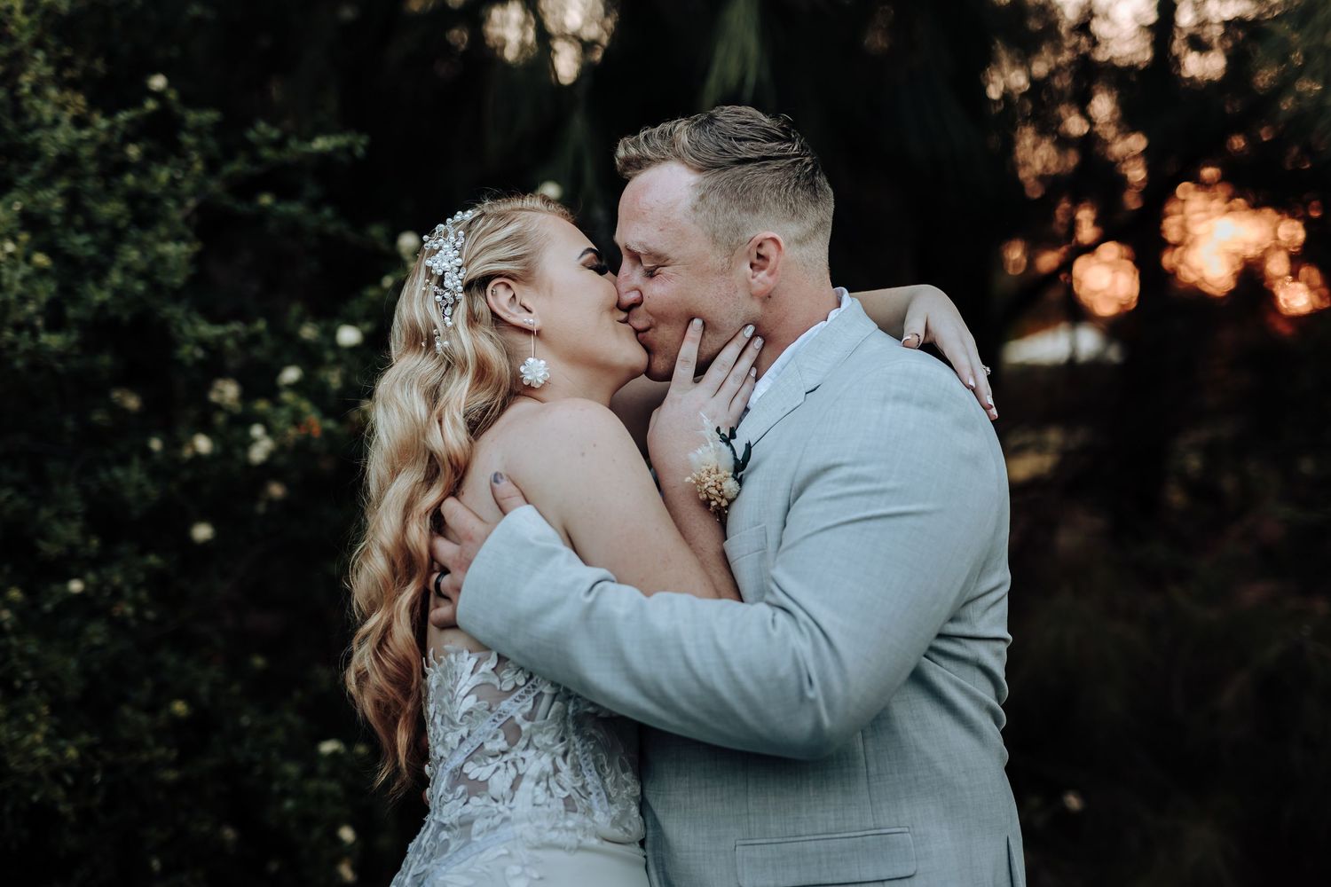 Romantic sunset wedding photo showing couple in emotional embrace outdoors.