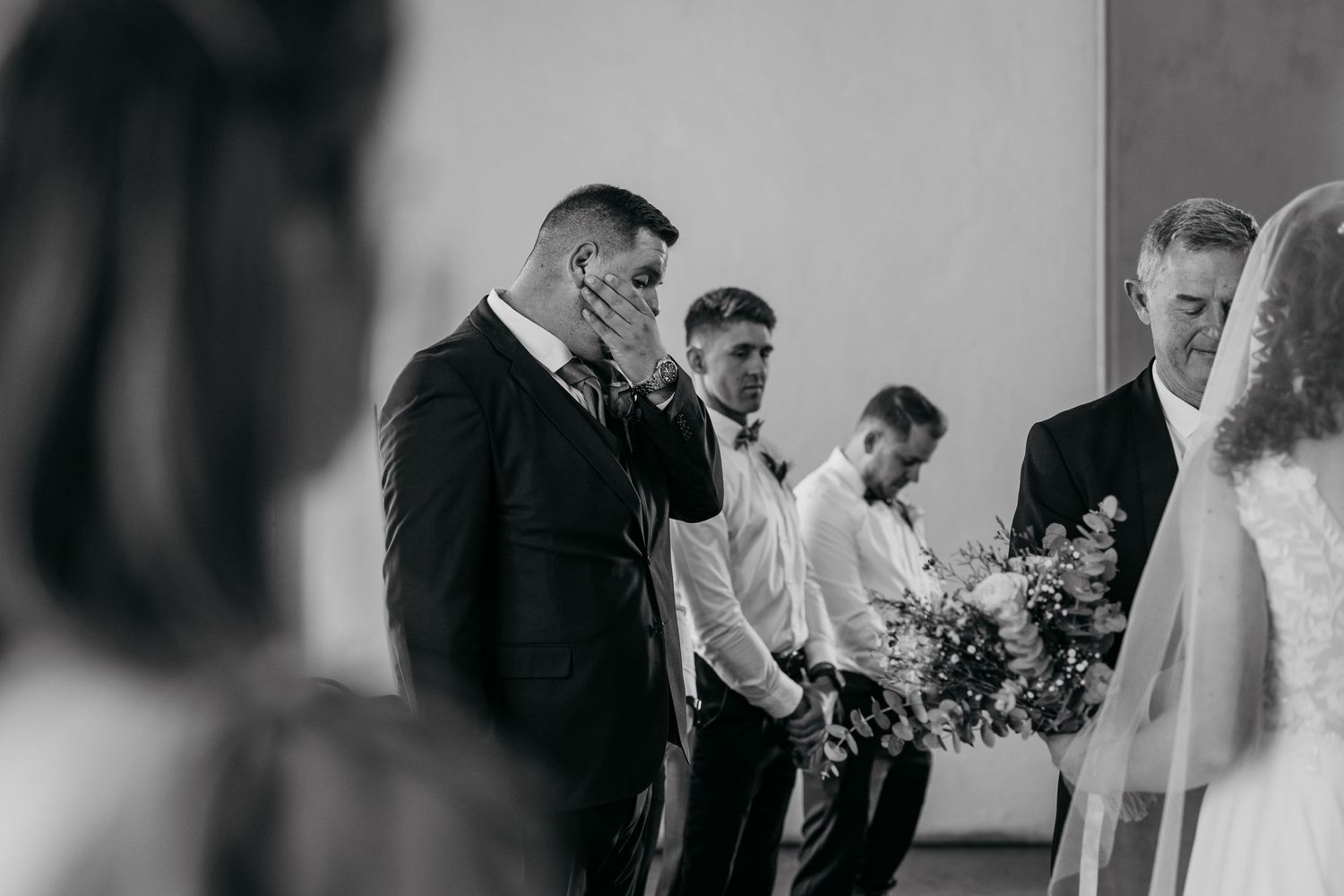 An intimate moment captured at a church altar during a wedding ceremony with guests looking on.