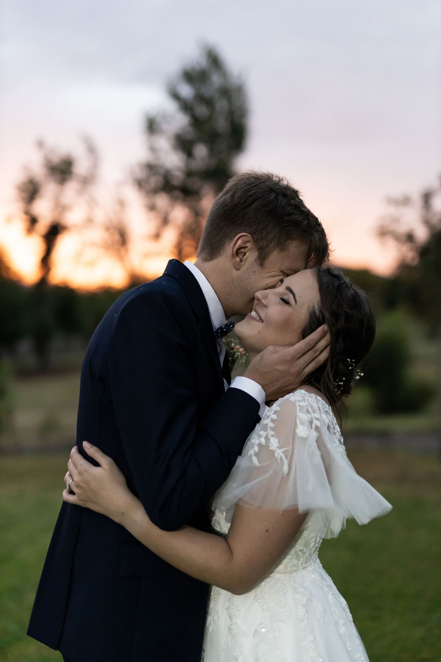 Intimate wedding portrait at sunset showing tender embrace between newlyweds.