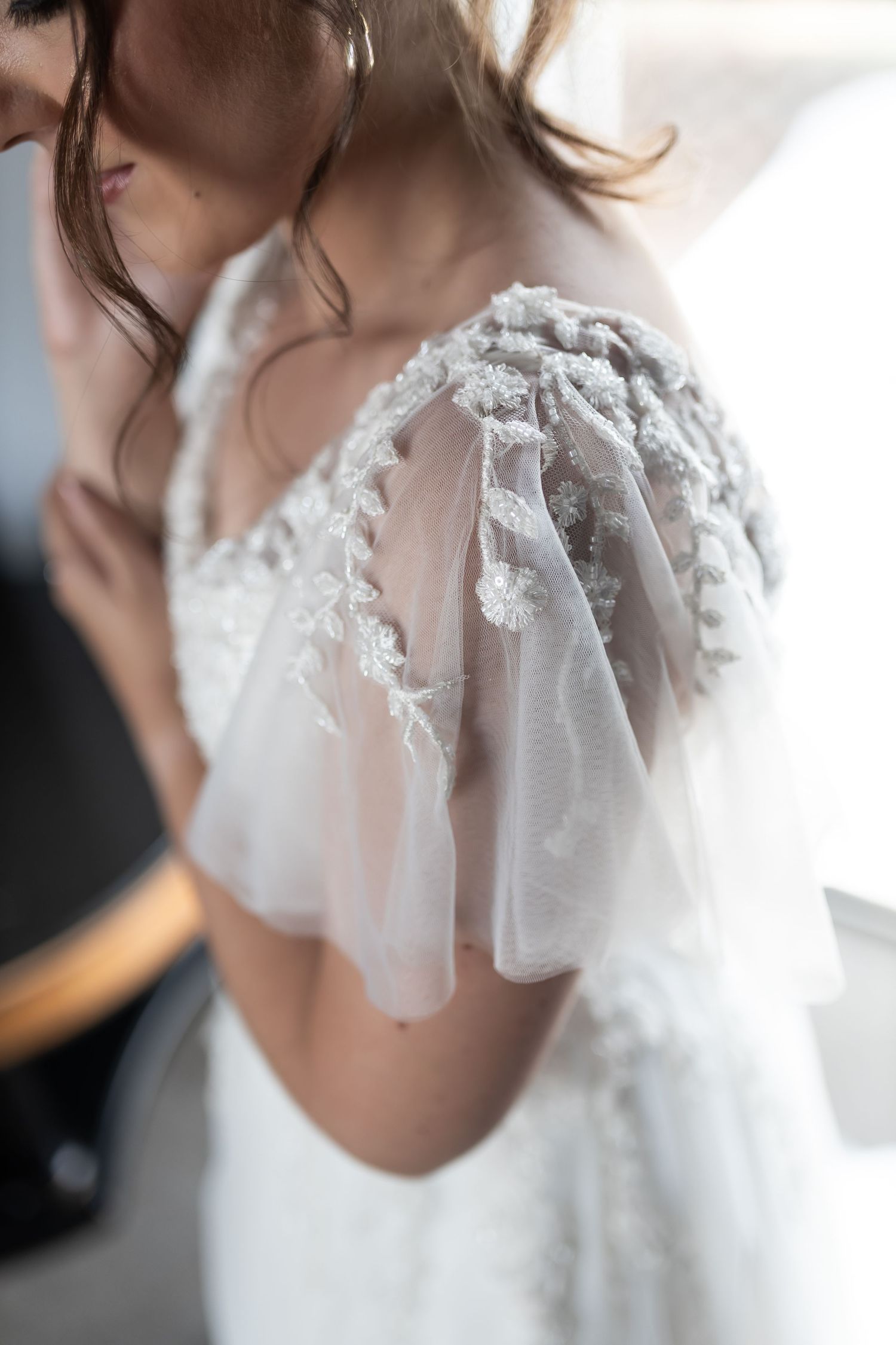 Detailed close-up of delicate lace sleeve on a white wedding gown.