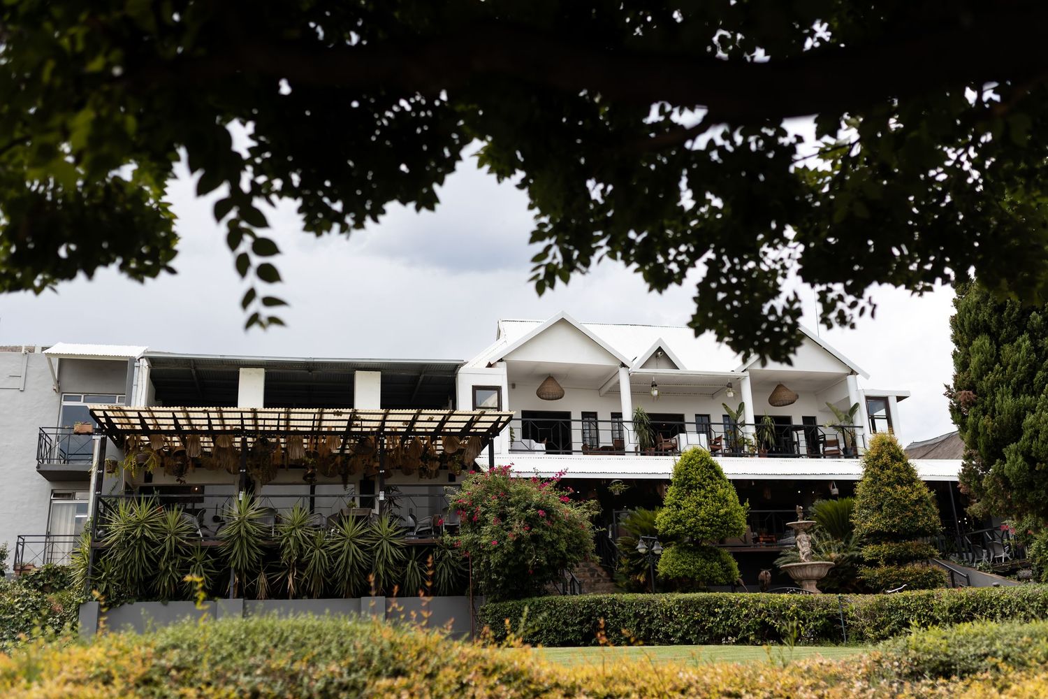 Elegant white wedding venue with balcony nestled among lush gardens.