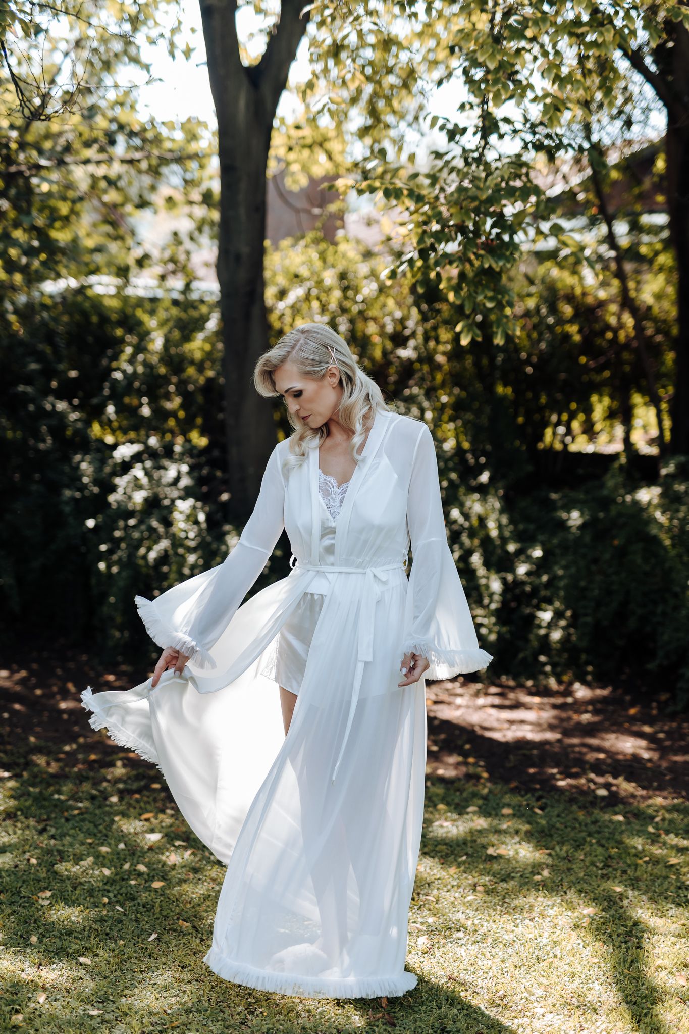 Flowing white wedding dress twirls in a sunny garden setting.