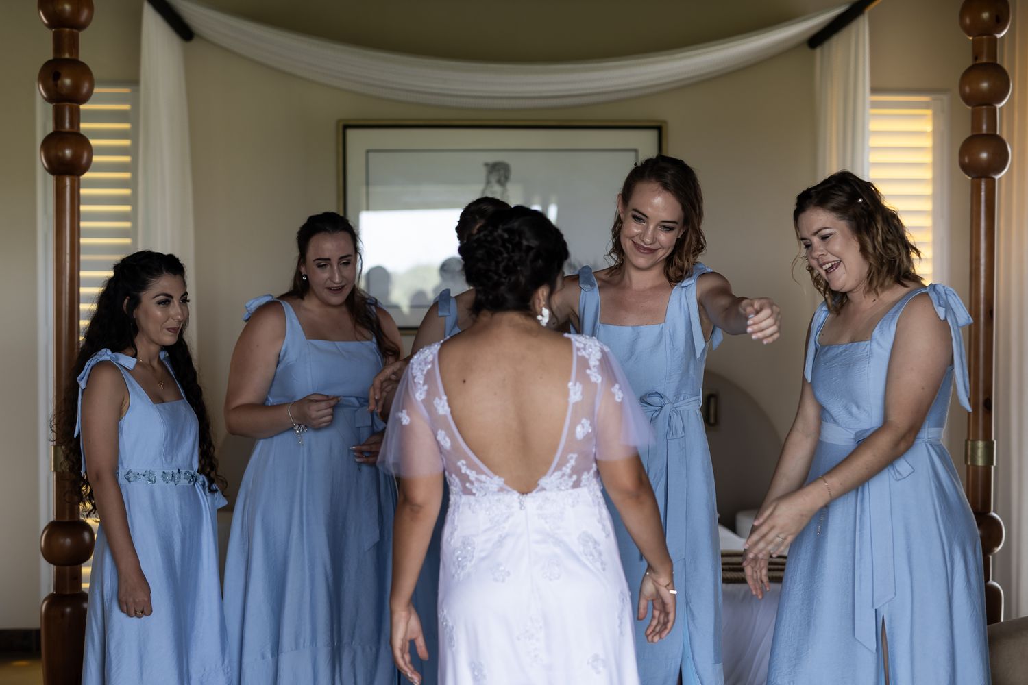 Bridesmaids in matching powder blue dresses share a moment with the bride in a white gown.