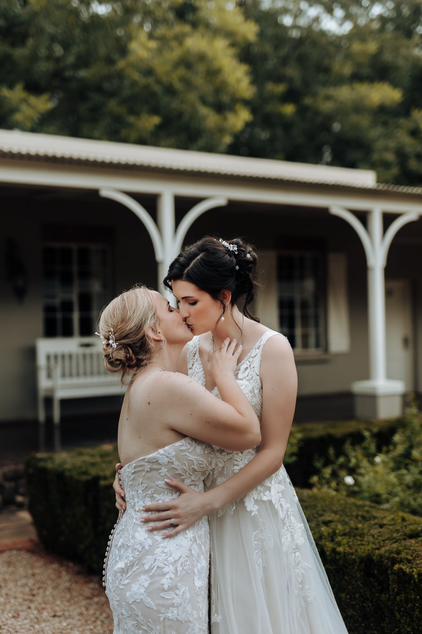 Intimate wedding portrait of couple sharing kiss on veranda with vintage architecture.