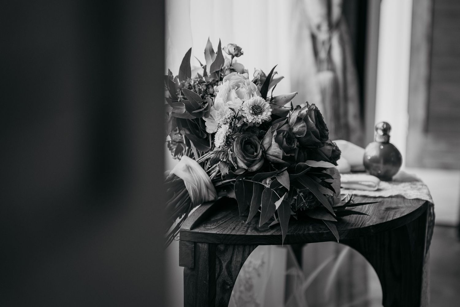 Black and white photograph of floral arrangement on wooden surface.