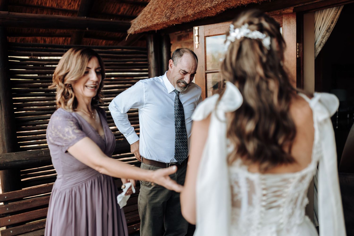 Intimate wedding preparation moment in a rustic barn with wooden slat walls.