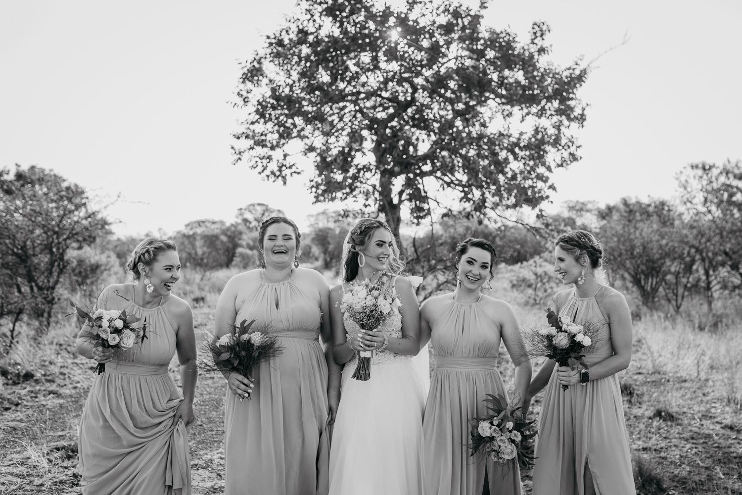 Black and white portrait of bridal party with matching dresses in outdoor setting.