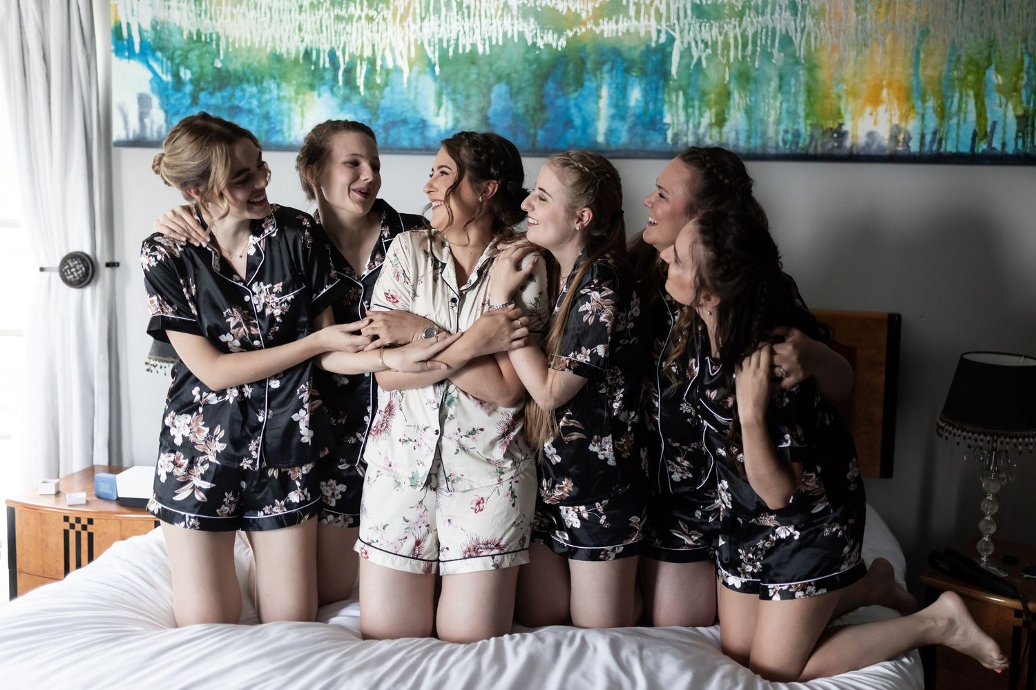 Friends in matching pajamas share joyful moment on bed during celebration.