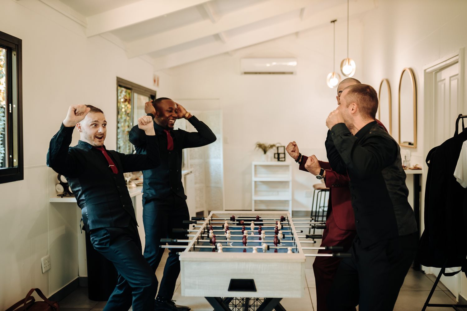 Energetic players celebrating and cheering during an intense foosball match.