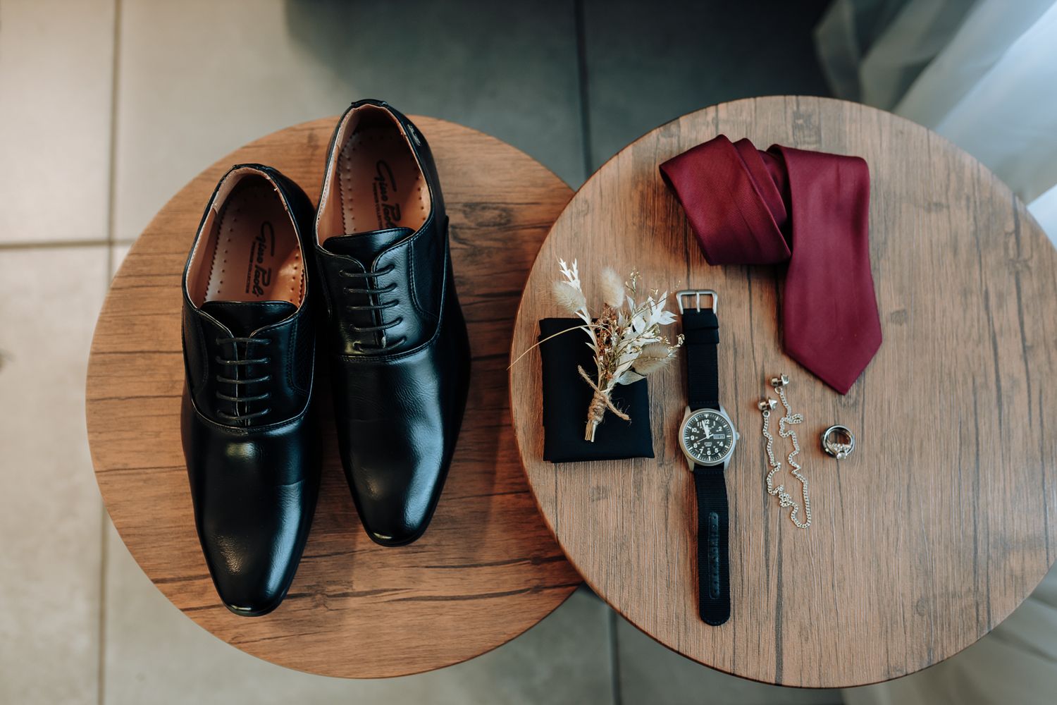 Men's formal black shoes and accessories arranged on wooden round table.
