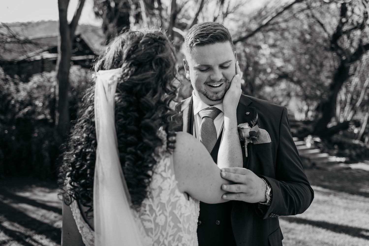 A candid black and white wedding moment showing emotional first look between couple outside in natural lighting.