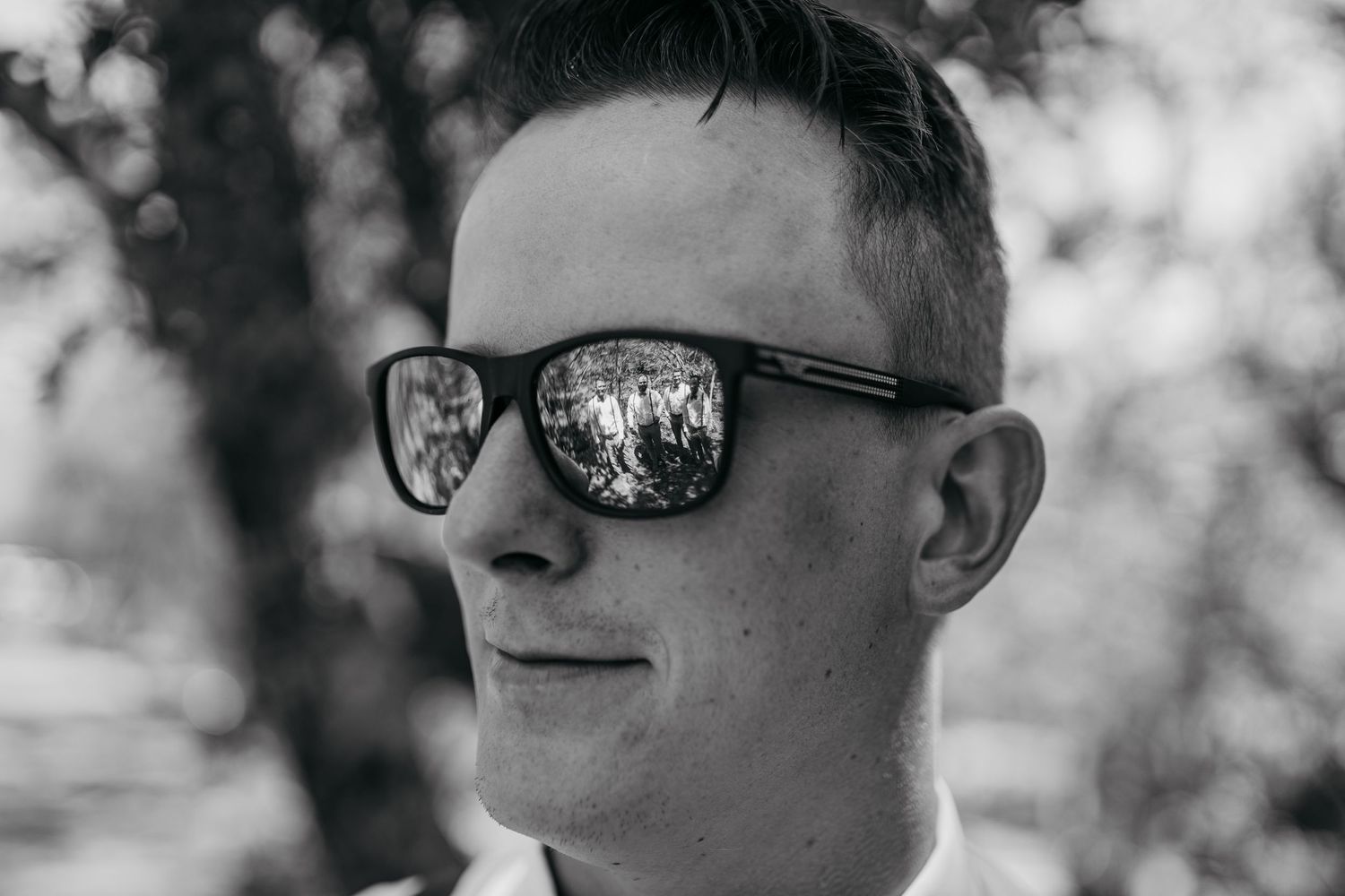 Close-up portrait of person wearing reflective sunglasses in black and white photography.