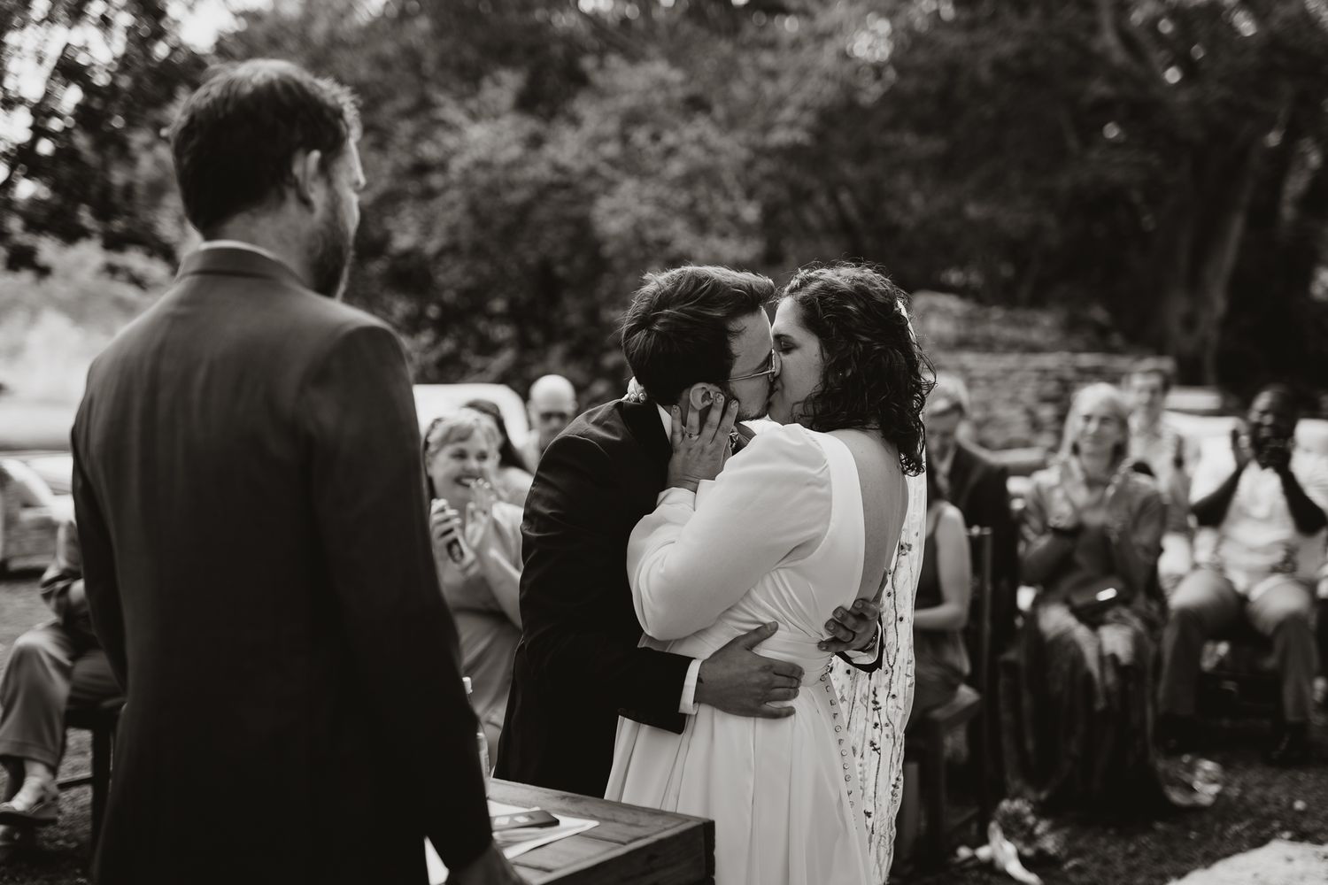 A black and white capture of a tender wedding ceremony moment in a garden setting.