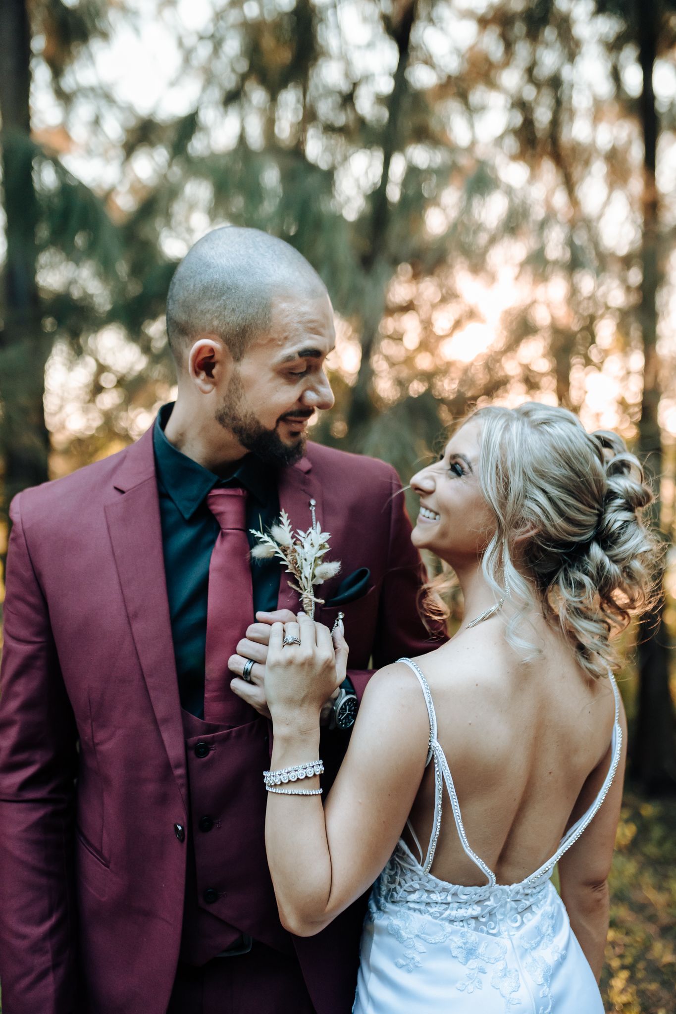 Intimate wedding moment captured in a forest setting during golden hour.