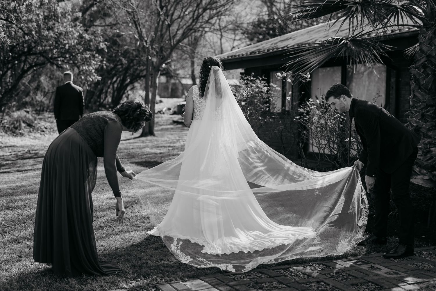 A series of black and white wedding photos showing the flowing movement of a bridal veil in an outdoor setting.