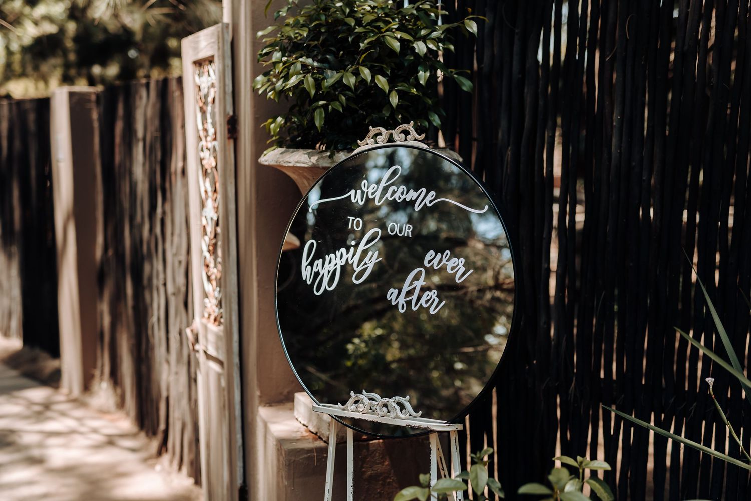 Round mirror wedding sign with calligraphy displayed outdoors.