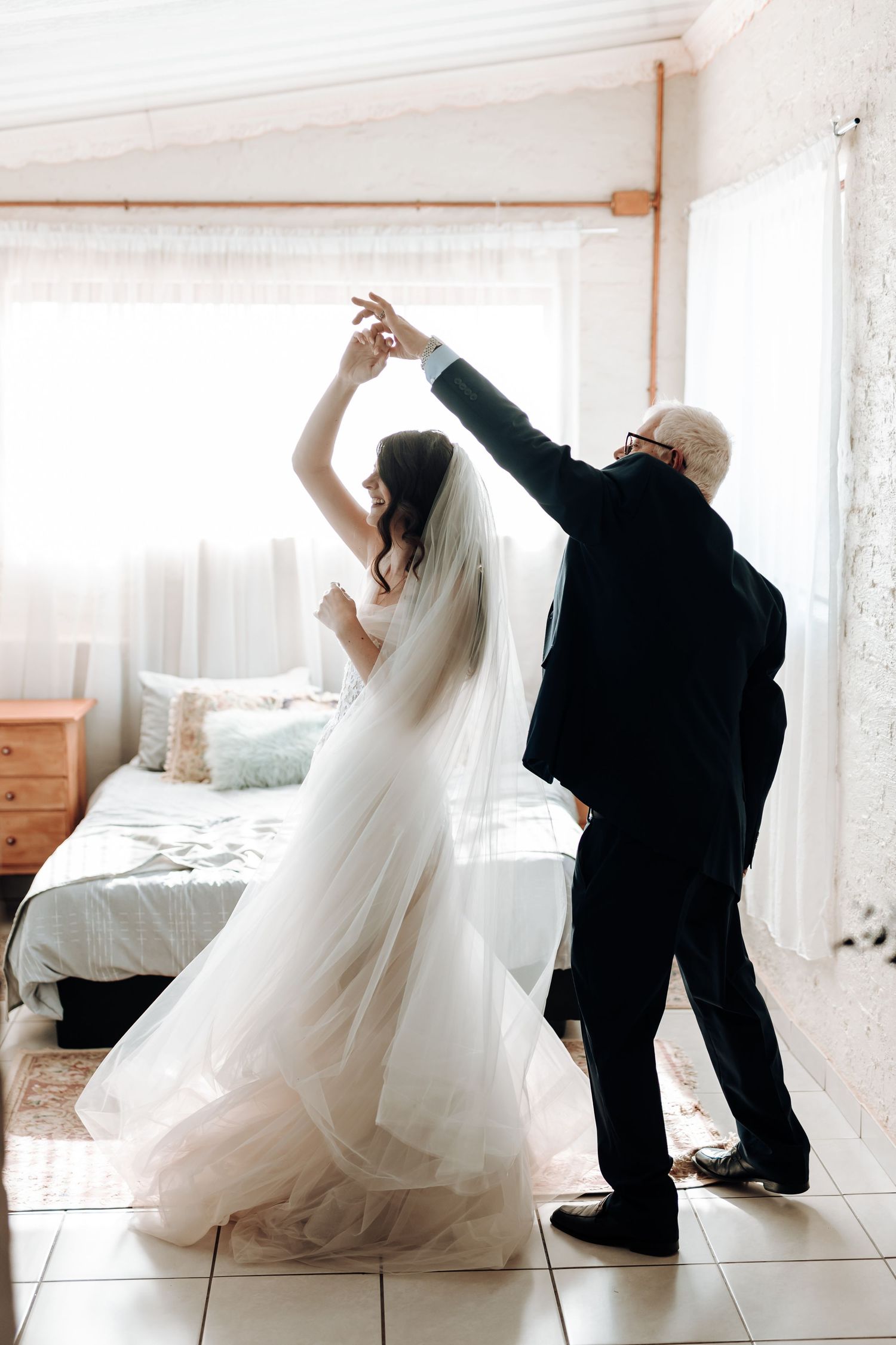 A touching moment of dancing between a bride in white and someone in formal attire.