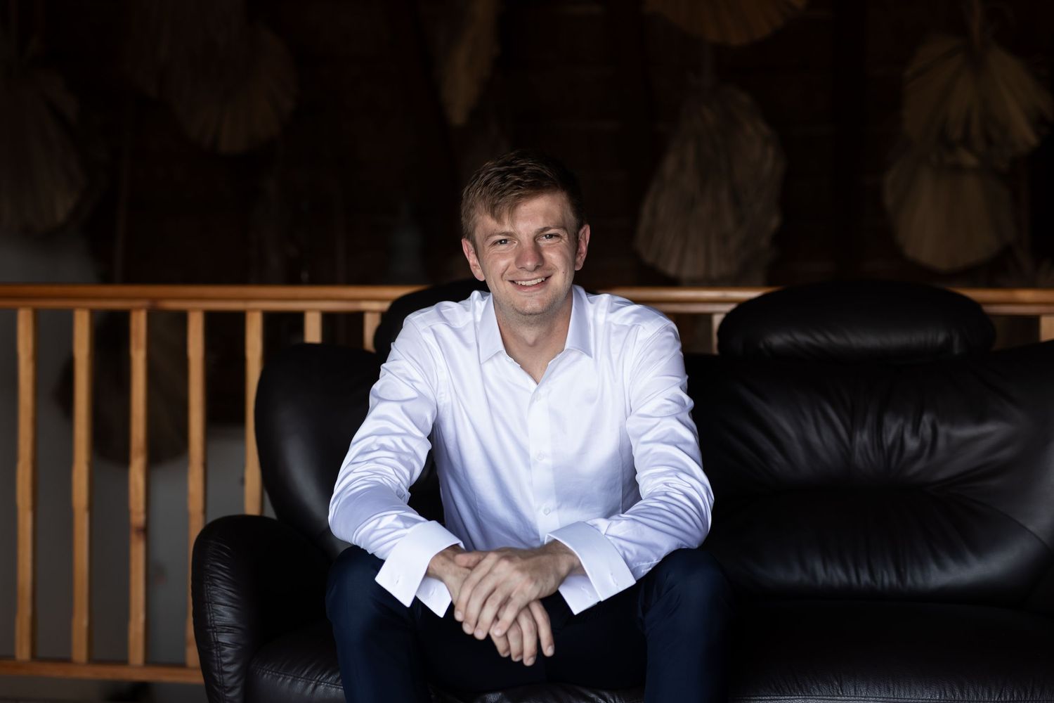 Formal portrait showing classic white shirt and navy pants in interior setting.