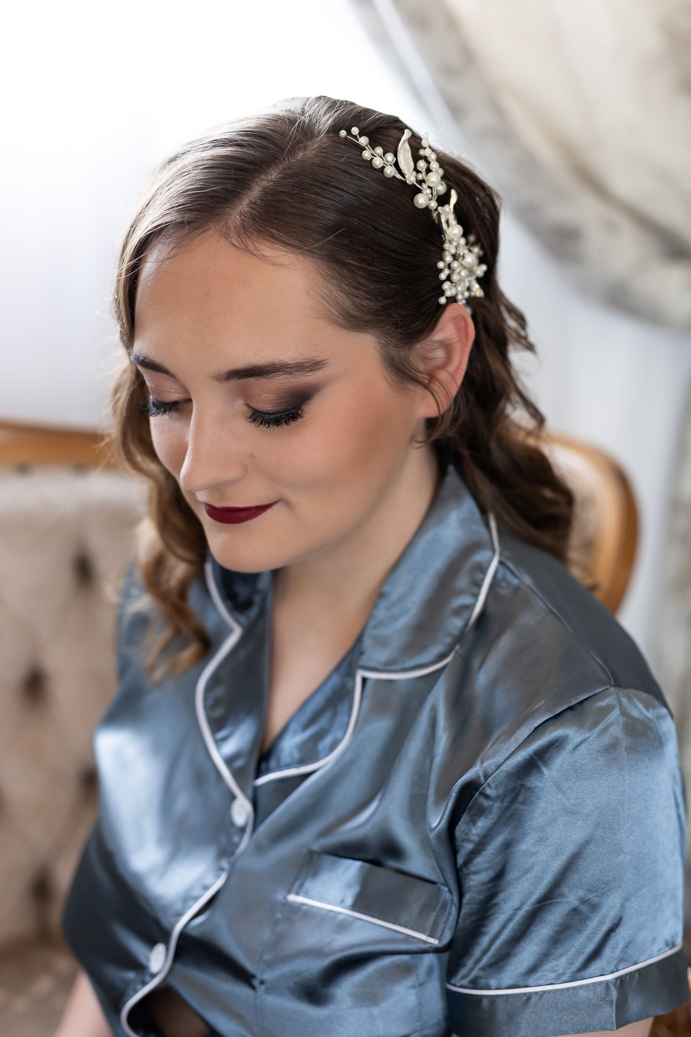 Close-up of elegant bridal makeup and hair accessory with silk pajamas.