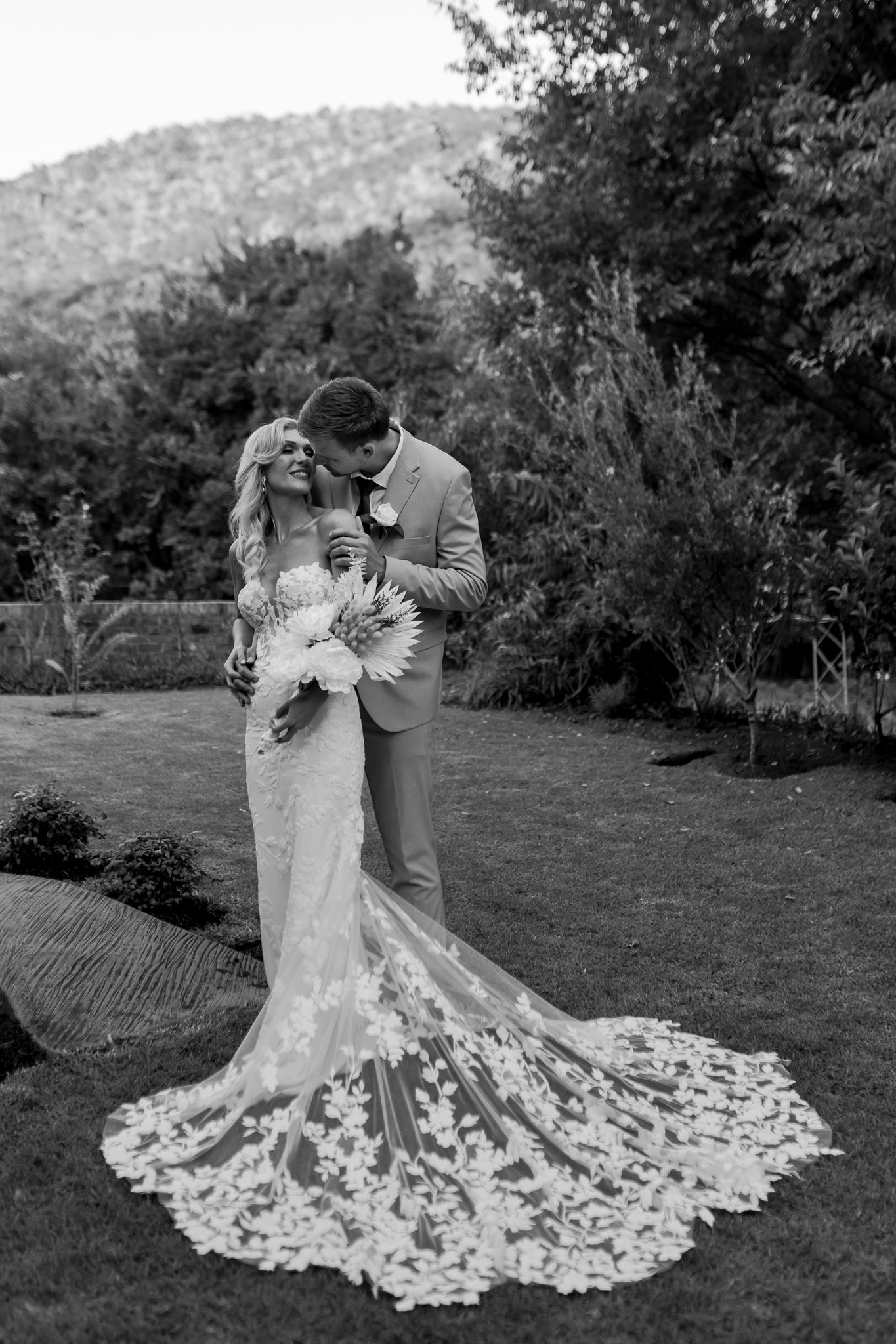 A romantic black and white wedding portrait captured in front of a mountain landscape.