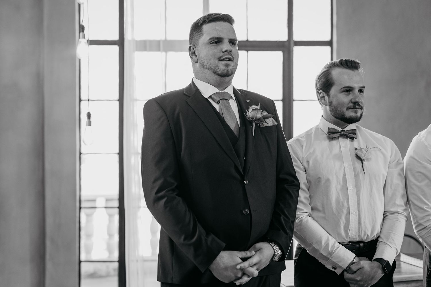 A black and white photograph showing a formal wedding party lining up at an indoor venue.