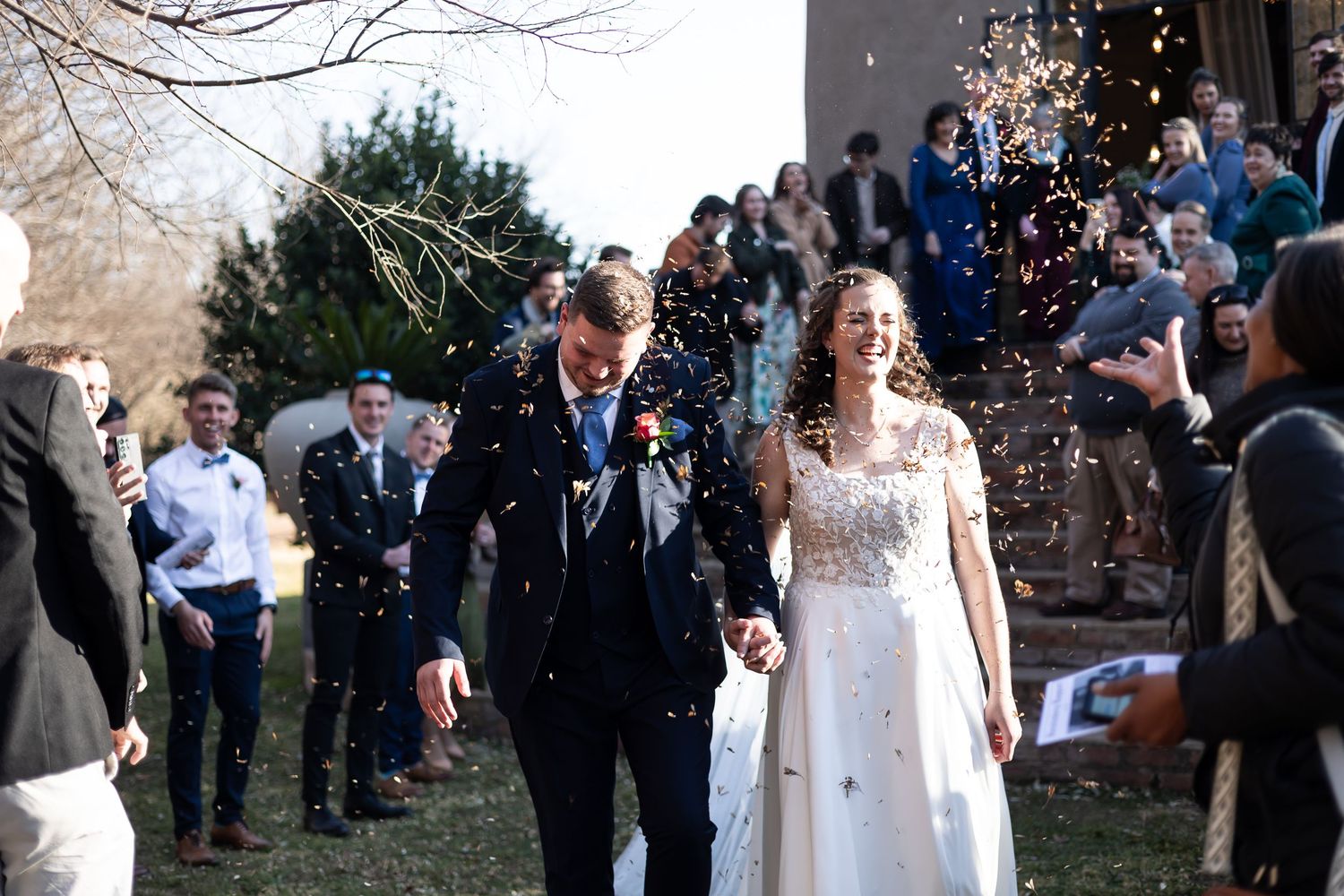 Wedding guests celebrate with joy as confetti falls during an outdoor winter ceremony at dusk.
