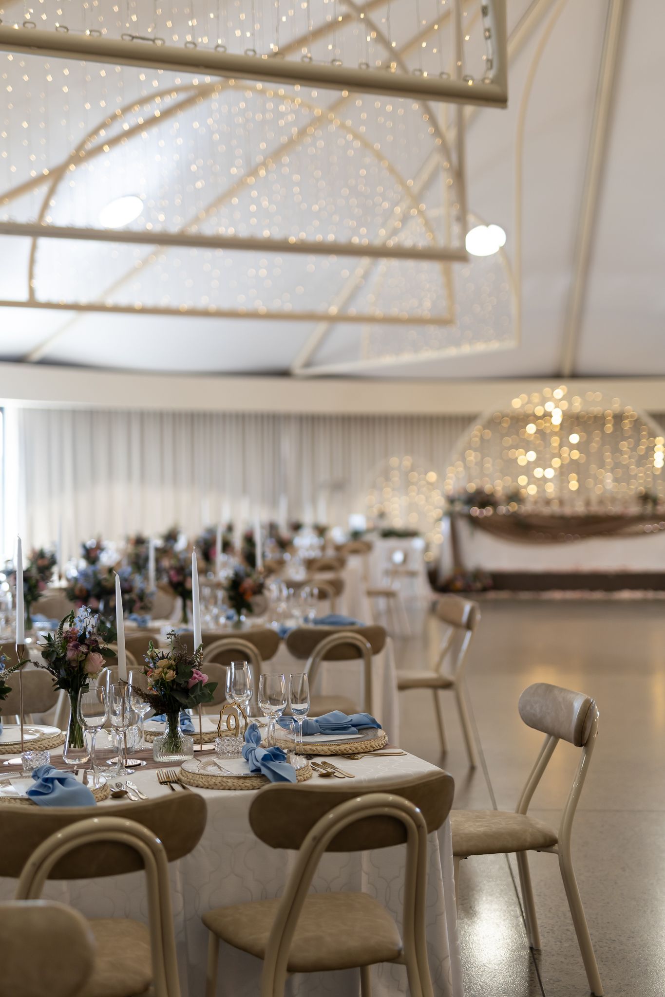 Wedding reception venue with twinkling lights, nautical decor, and elegant table settings.