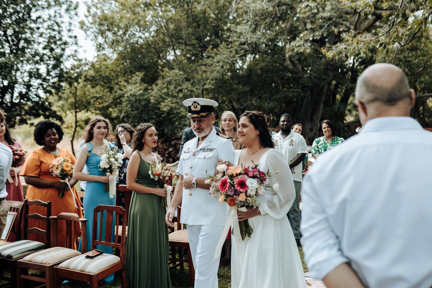 Wedding ceremony procession in a garden setting with rustic decor and natural lighting.