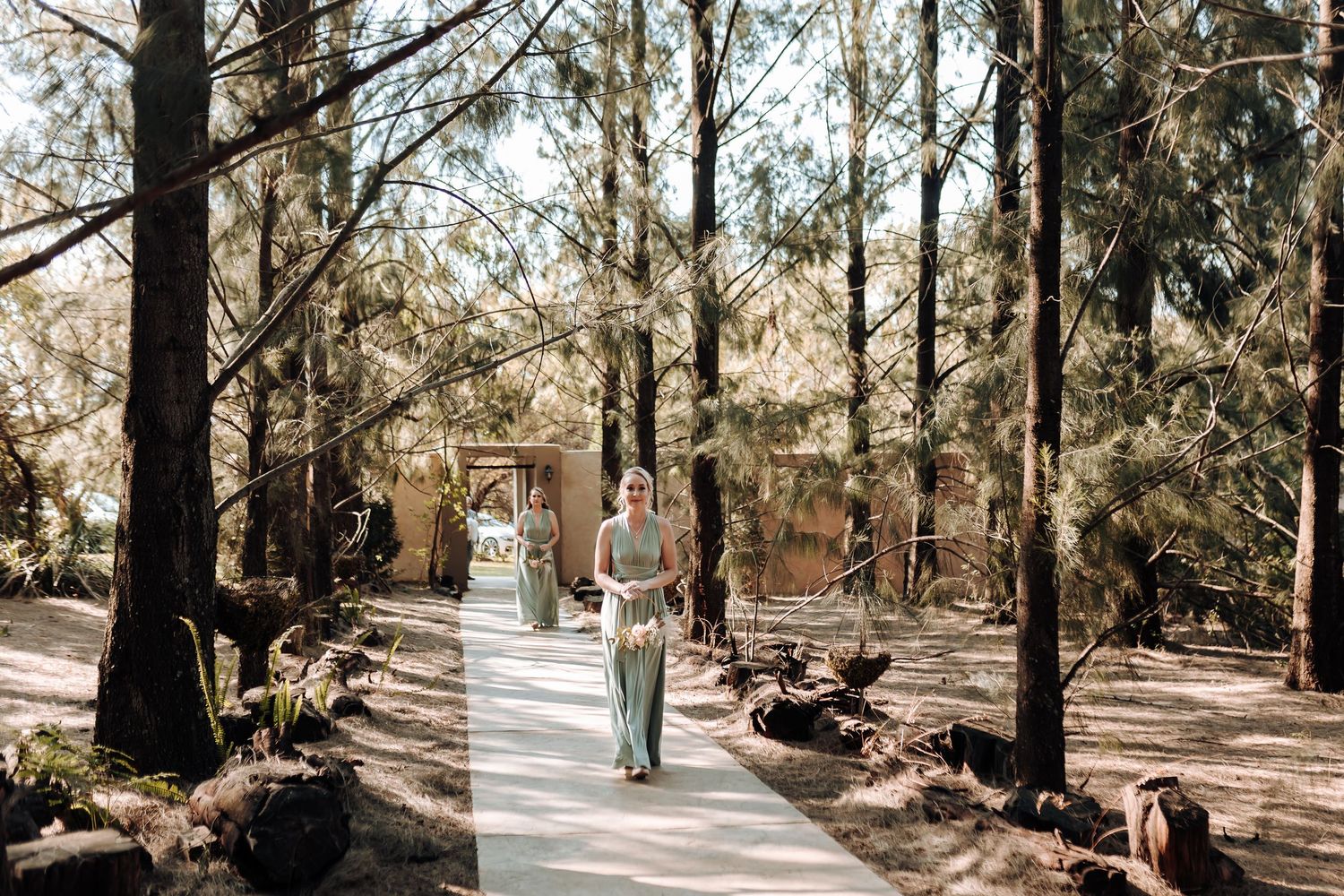 Figure walks down tree-lined path in outdoor wedding venue setting.