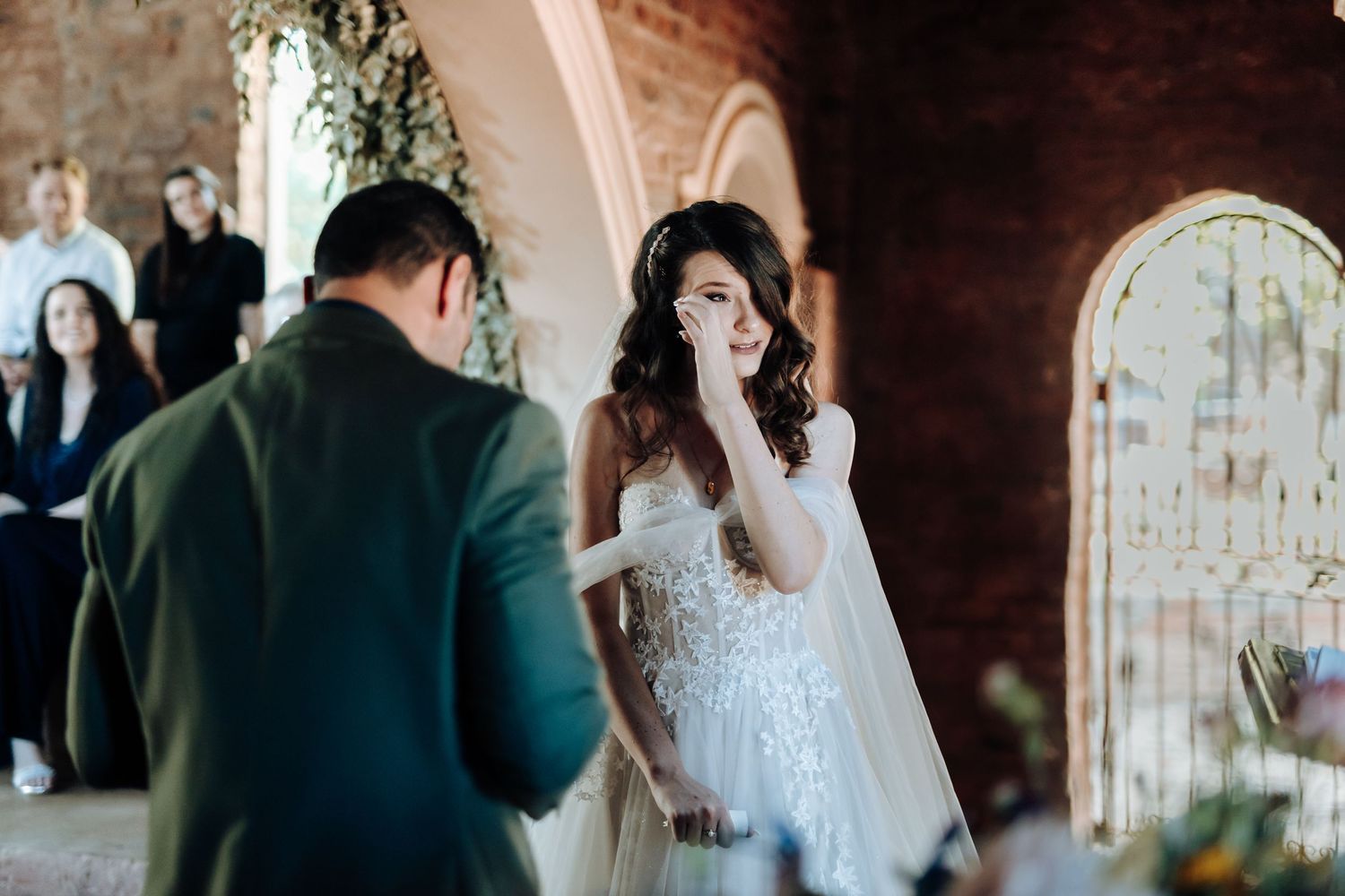 Emotional wedding ceremony moment as couple shares tearful exchange under arched doorway.