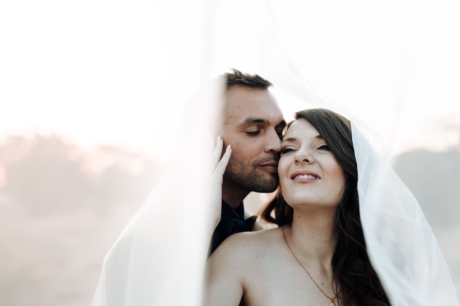 Intimate close-up of a tender moment between newlyweds against soft light.