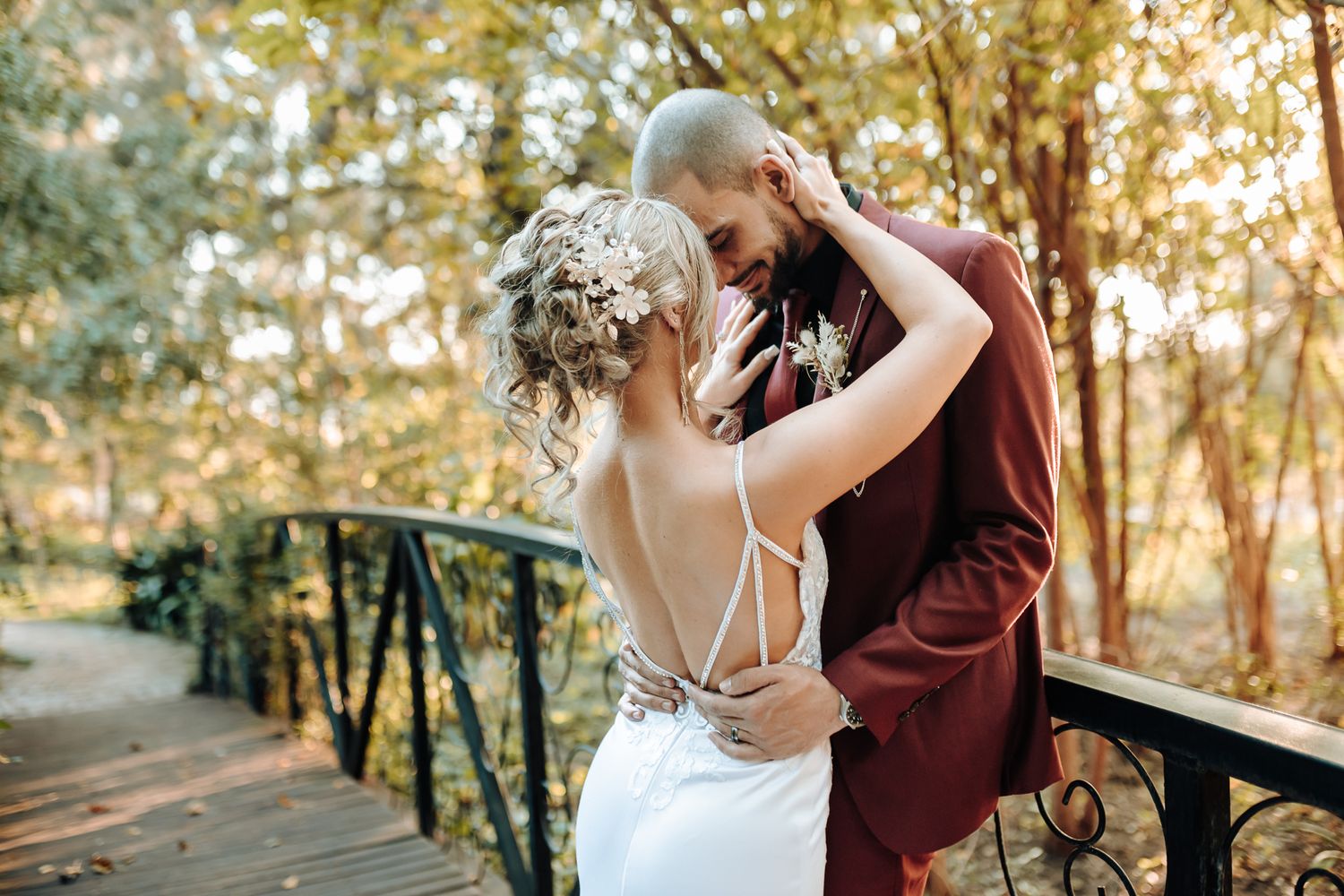 A romantic moment between newlyweds on a rustic bridge in warm afternoon light.