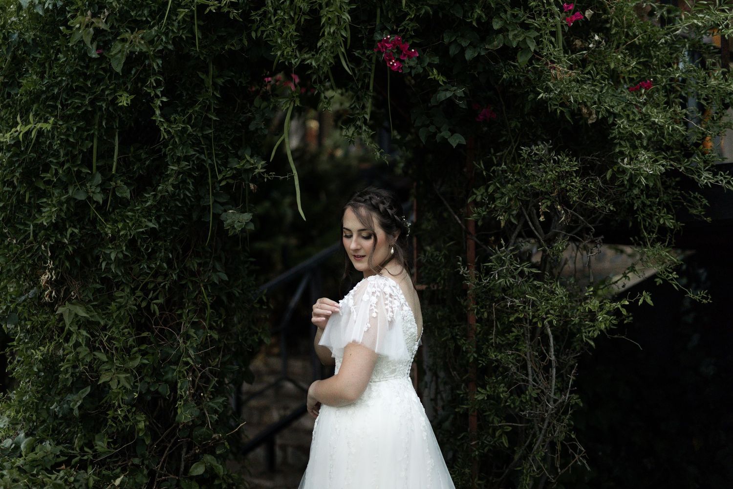 Classic white wedding dress with short sleeves among flowering garden vines.