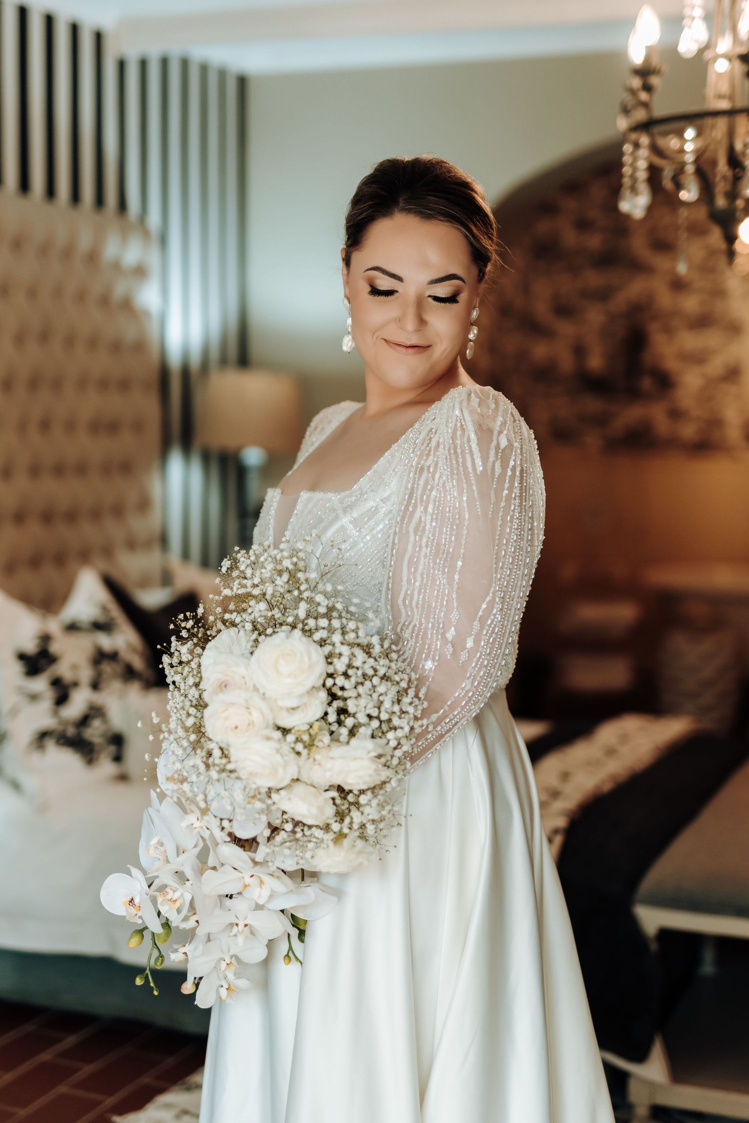 Bride in long sleeve white gown holding delicate white and baby's breath bouquet.