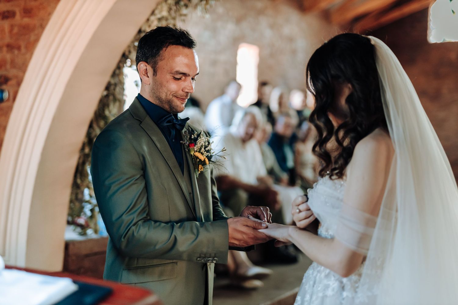 A couple shares an intimate moment during their wedding ceremony in a rustic brick venue.