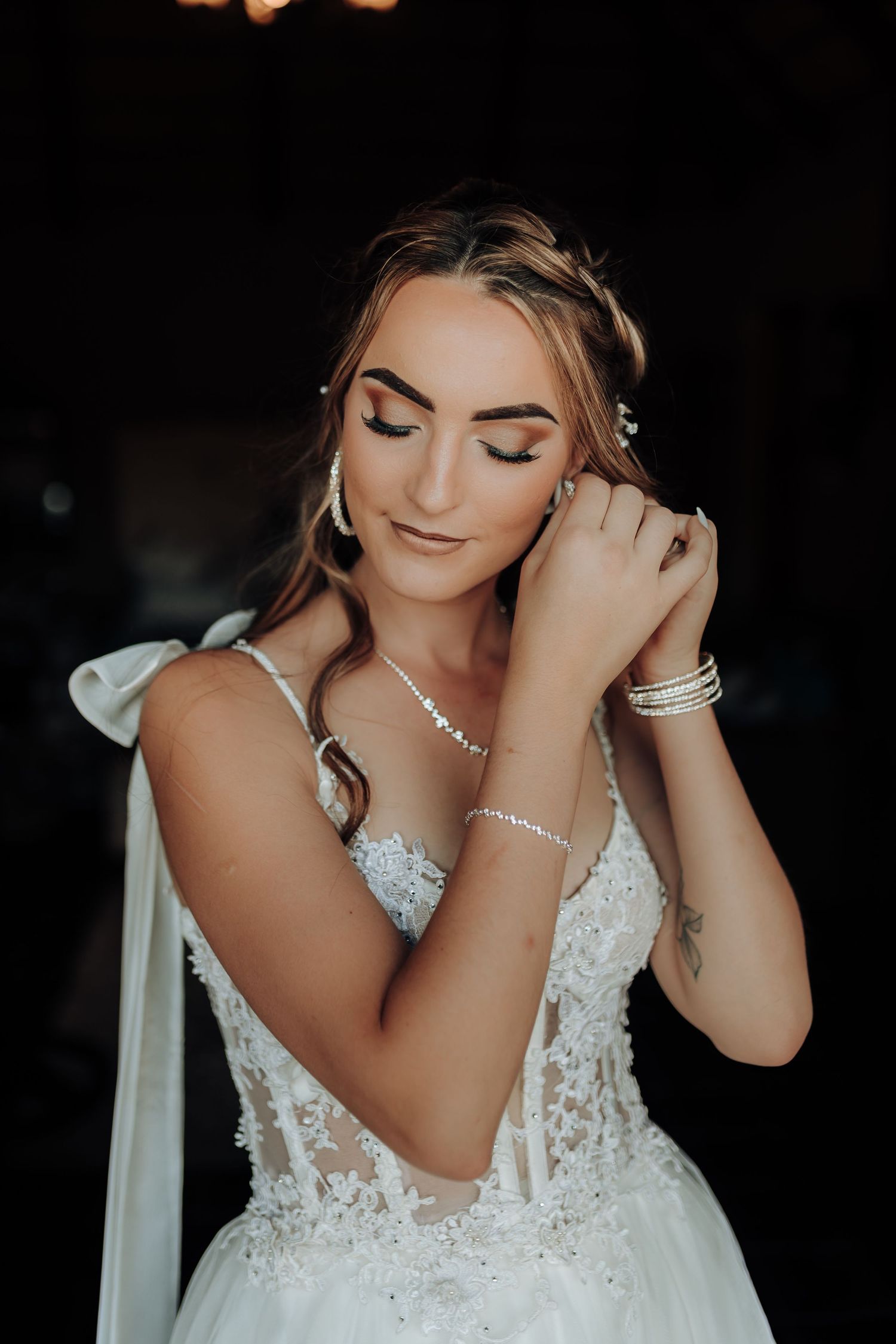 Close up of bride wearing delicate jewelry and lace wedding gown with soft makeup.