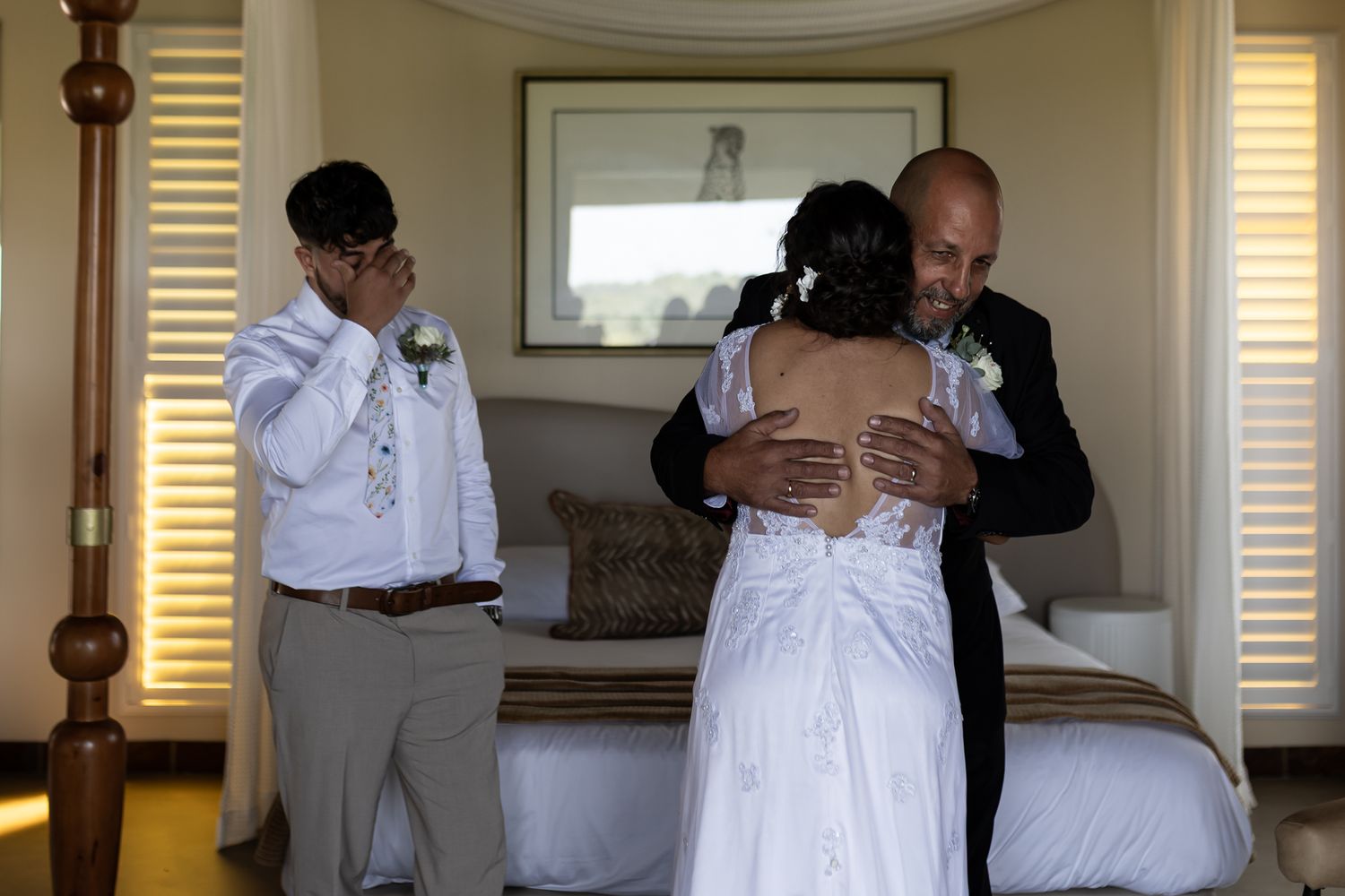 Tender embrace shared during private wedding moment in sunlit bedroom.
