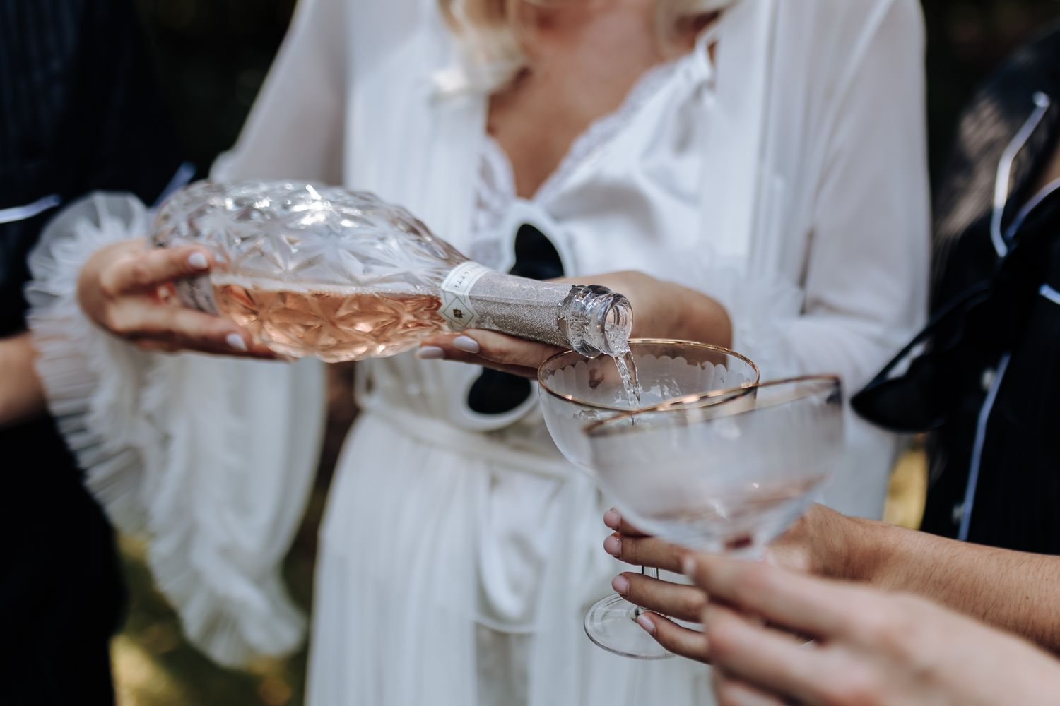 Champagne being poured into a glass at a wedding celebration in an elegant outdoor setting.