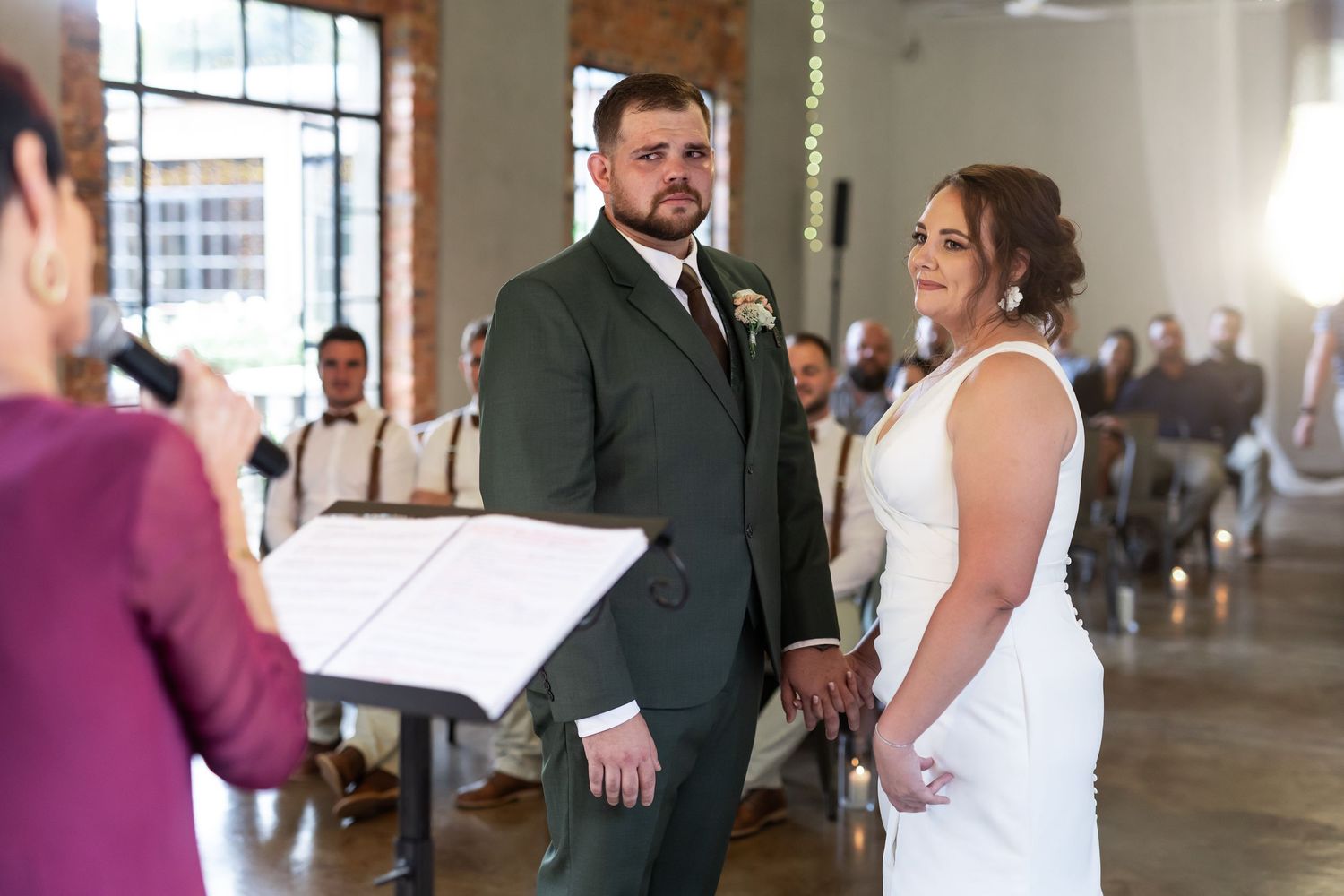 A couple stands before an officiant during their wedding ceremony in an elegant indoor venue.