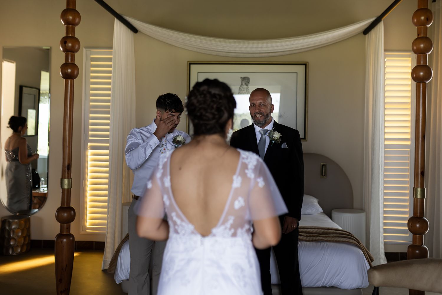 Emotional first look moment in bedroom between wedding couple with mirror reflection.