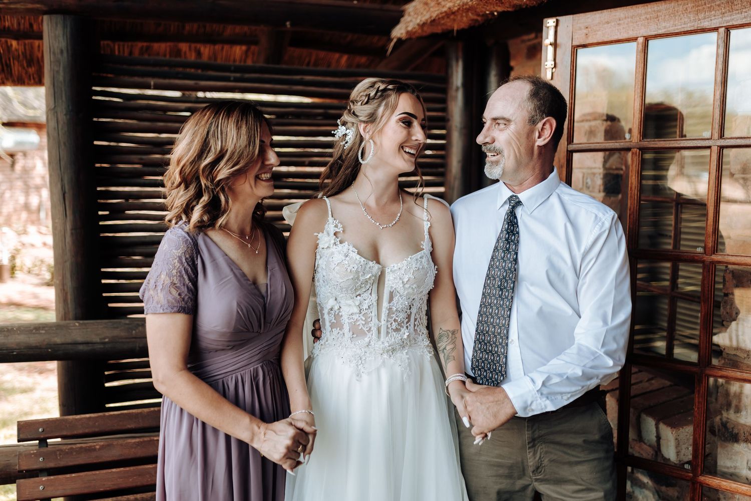 Wedding party shares candid moment together in rustic barn setting with natural light.