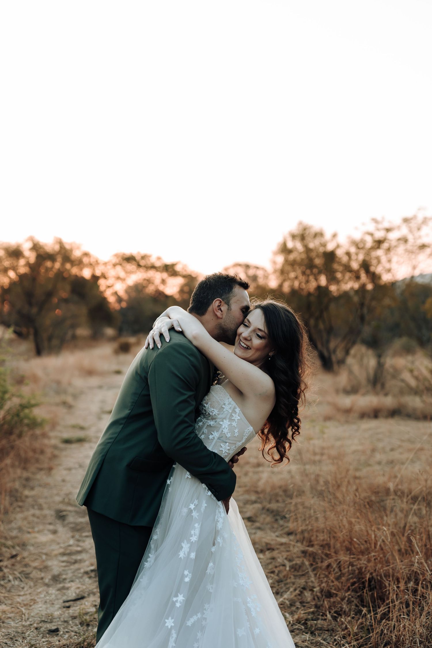 A couple shares a romantic dip pose on a rustic path at sunset.