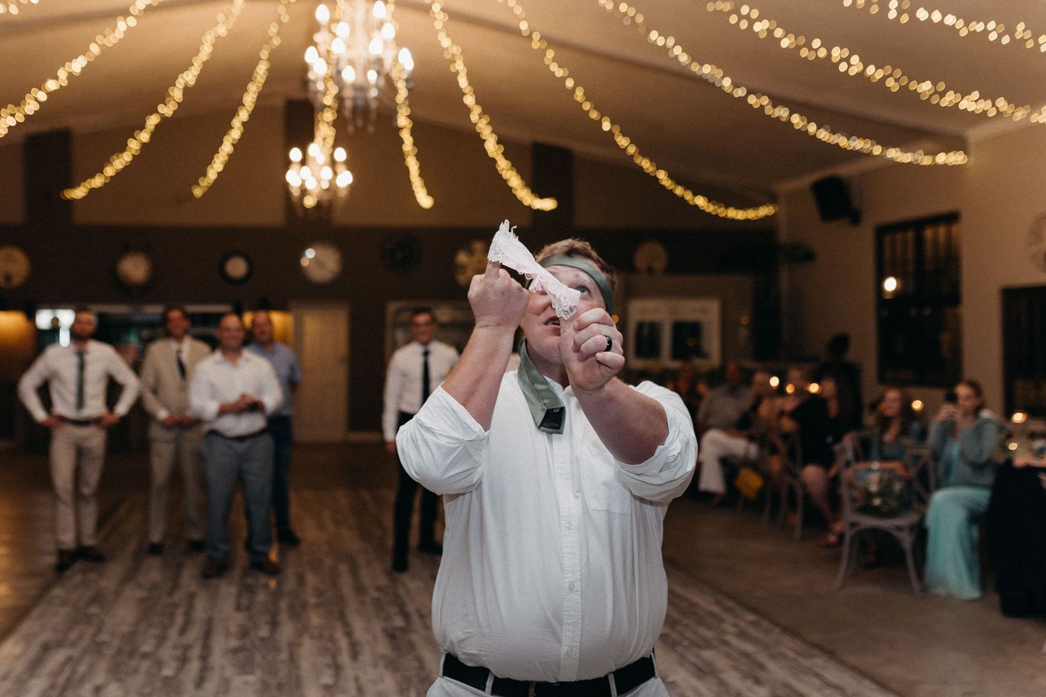 A guest dances enthusiastically under string lights at a wedding reception.