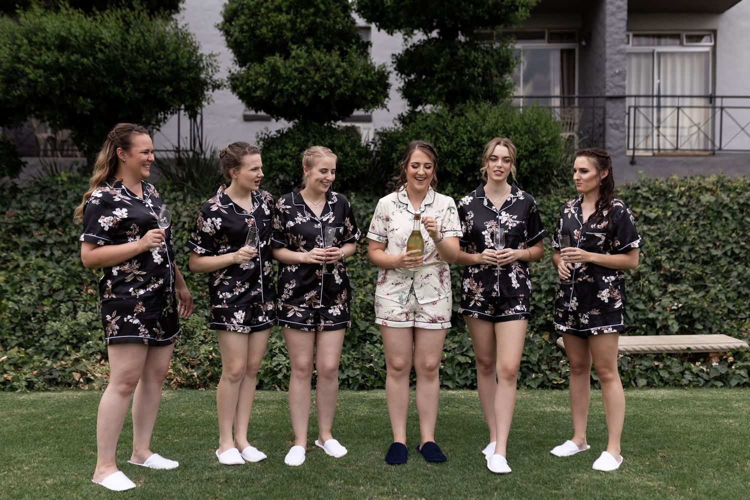 Group in coordinated black floral outfits poses together on lawn.