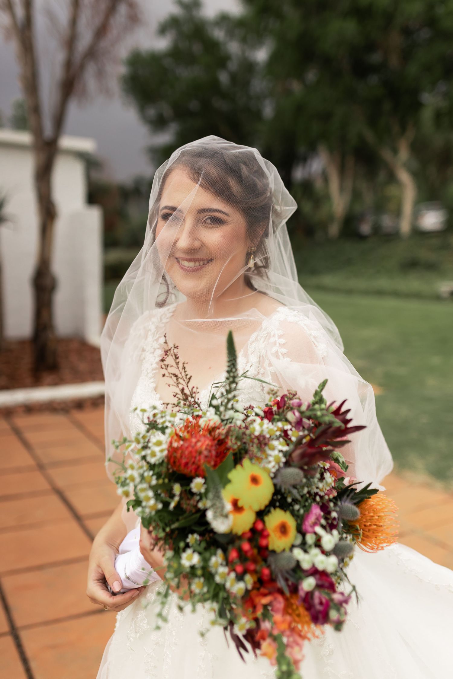 A bridal portrait featuring a colorful wildflower bouquet and delicate lace veil.