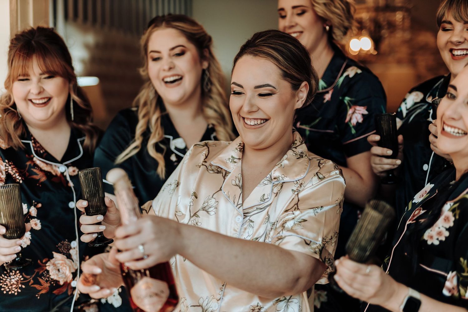 Group in matching floral robes celebrating during pre-wedding preparations.