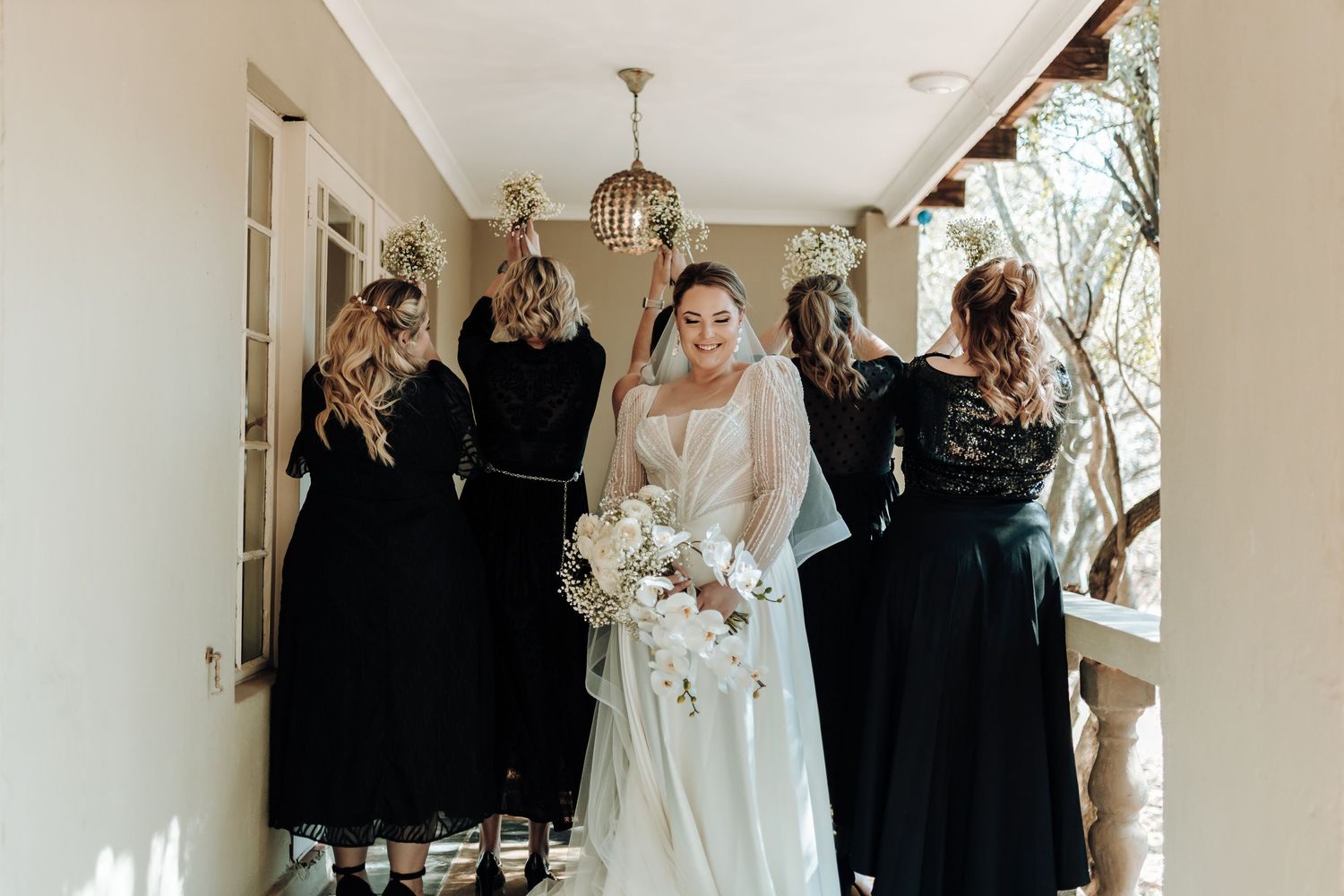 Joyful bridal party celebrates in a hallway with bride in flowing white dress.