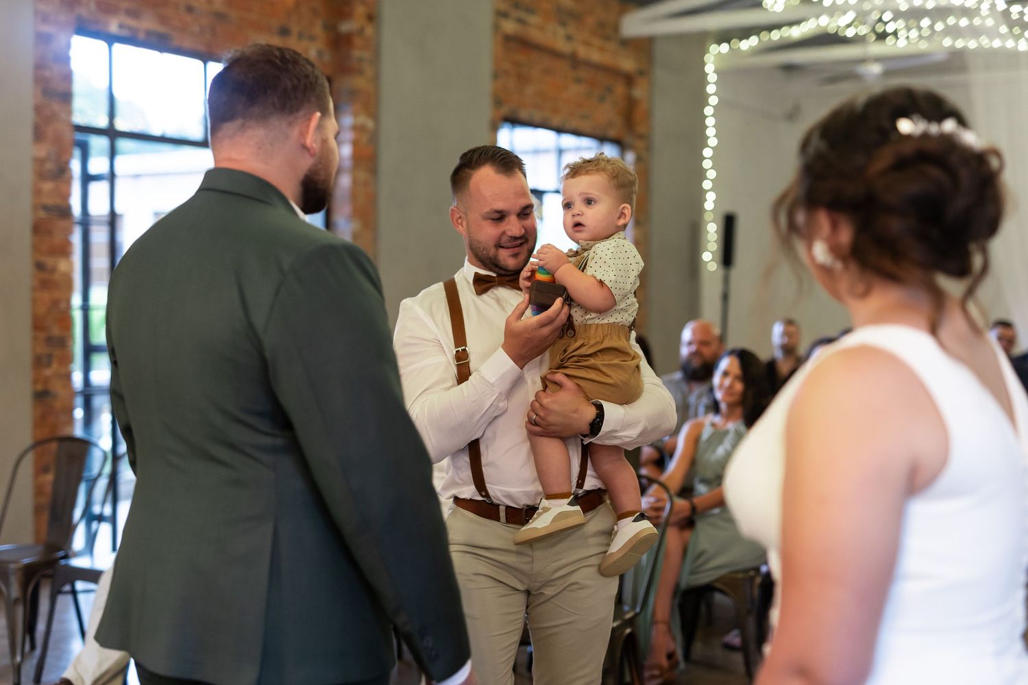 Wedding ceremony moment with formal attire and decorative lighting.
