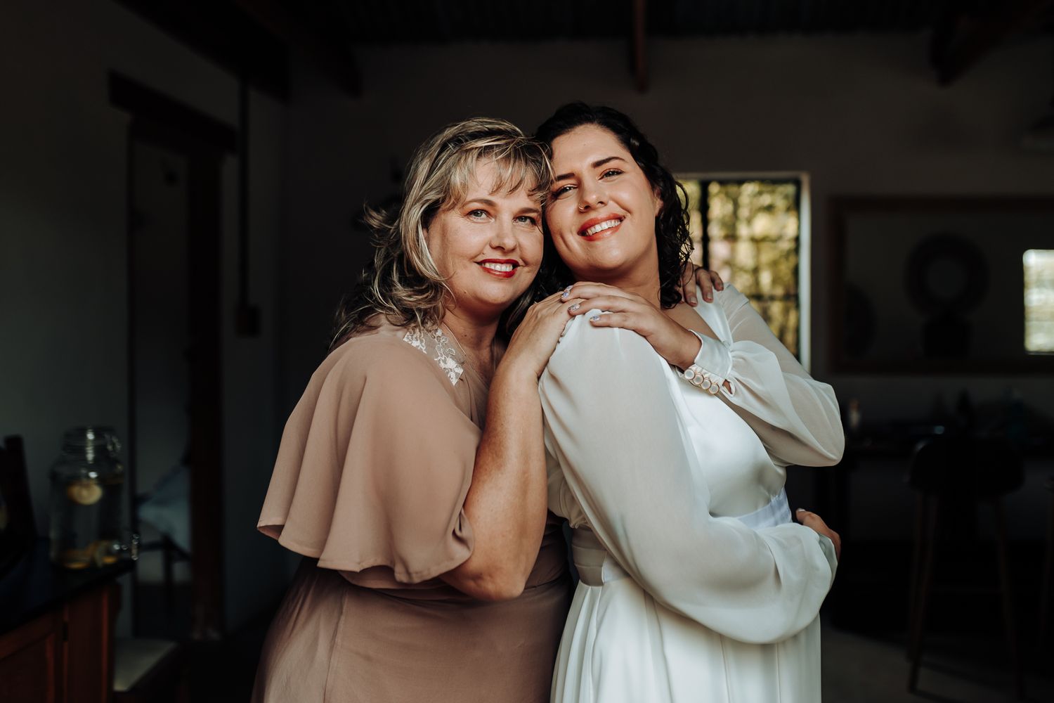 Candid moment showing two people in formal attire embracing and smiling warmly.